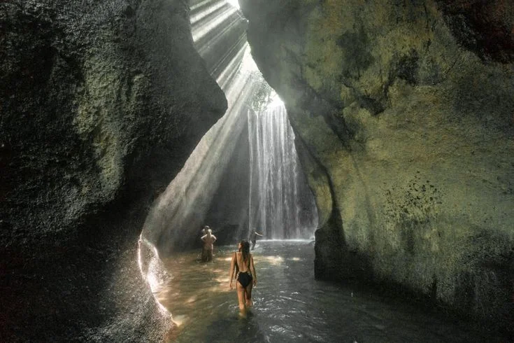 Tukad Cepung cave waterfall with sun beams cutting through the canopy
