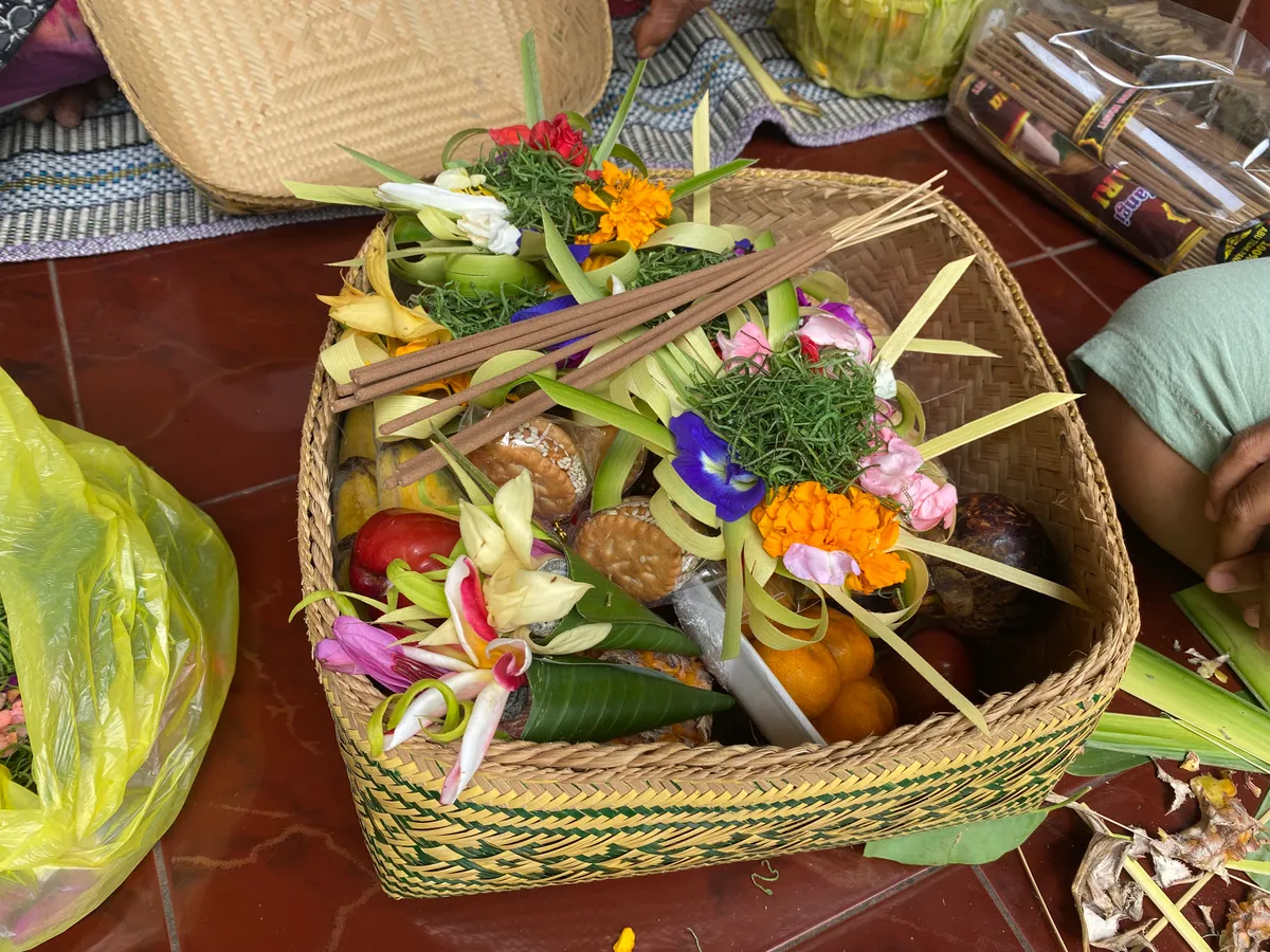Close-up of a finished canang sari with fresh tropical flowers